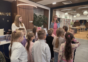 Grupa dzieci stoi w bibliotece.