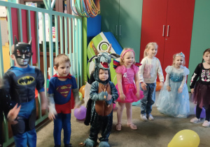 Dzieci przebrane za postacie z bajek, tańczą stojąc w półokręgu.
