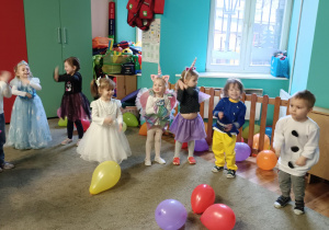Dzieci przebrane za postacie z bajek, tańczą stojąc w półokręgu.