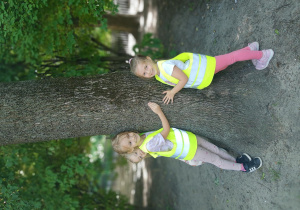 Dziewczynki przytulają się do drzewa.