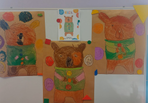 Tablica a na niej prace Dzieci przedstawiające niedźwiadka Guzika
