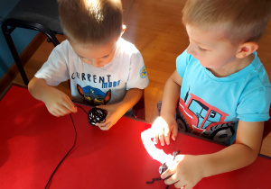 dwóch chłopców siedzi przy stoliku, nawijają włóczkę na styropianowa kulkę.