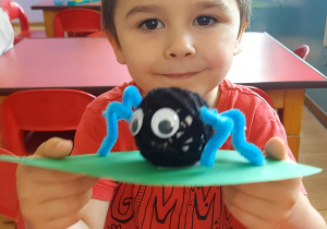 Chłopiec pokazuje pajączka z włóczkę.