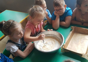 Każde dziecko dodało jakiś składnik. Na zdjęciu dziewczynka miesza ciasto aby wszystkie składniki dobrze się połączyły.