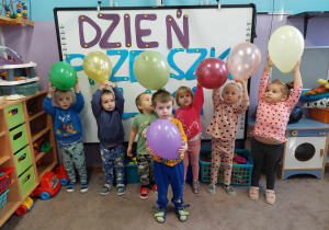 Dzieci pozują do zdjęcia na tle Napisu"Dzień Przedszkolaka". w dłoniach każde dziecko trzyma balon.