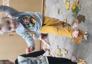 Chłopiec podnosi palcami stóp leżące liście.