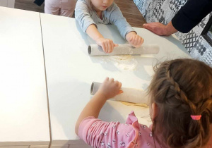 Dziewczynki wałkują ciasto na pyszne, słodkie bułeczki.