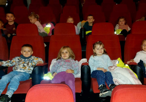 Dzieci siedzą w sali kinowej i czekają na projekcie filmu.