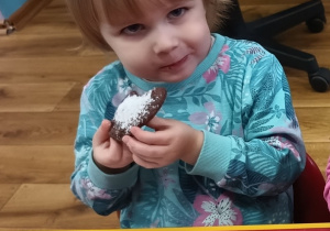 Dziewczynka z apetytem je upieczone ciastko.