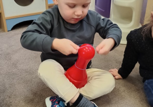 Chłopiec próbuje mocno rozciągnąć gumkę.