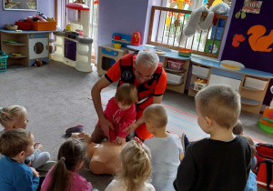 Ratownik pomaga dziecku wykonać masaż serca.