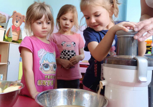 Dziewczynki robią sok z jabłek przy pomocy sokowirówki.