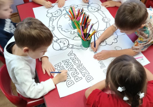 Dzieci z pierwszego stolika wspólnie kolorują mega kolorowankę.