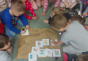 Dzieci przyklejają ilustracje do wspólnego plakatu informującego o ta\k ważnym dniu.