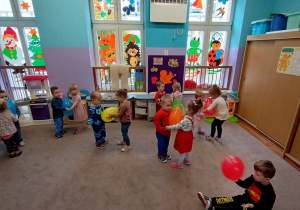 Dzieci tańczą w parach trzymając między sobą balon.