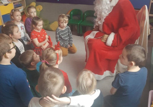 Dzieci siedzą przed Mikołajem, z którym chętnie rozmawiają.