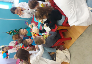 Dzieci siedzą przy stolikach i poznają wyposażenie torby lekarskiej.