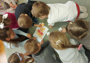 Inna grupa dzieci układa puzzle misia.