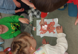 Grupa dzieci układa puzzle misia