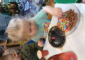 Dziewczynka wybiera czerwone cukiereczki i układa je na swoim talerzyku.