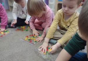 Dzieci manipulują guzikami umieszczonymi w torebkach strunowych.