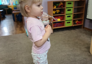 Dziewczynka przenosi małą kulkę za pomocą łyżki trzymanej w ustach.