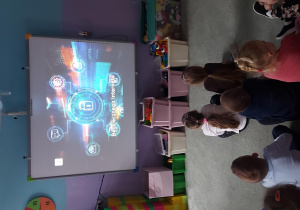 Dzieci siedzą przed tablicą interaktywną, na której wyświetlany jest film edukacyjny na temat bezpiecznego korzystania z internetu.