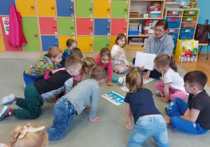 Dzieci oglądają ilustracje, które są na dywanie.