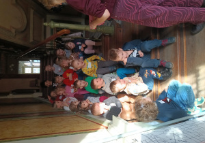 Dzieci siedzą na schodach willi i słuchają o Hilarym Majewskim.