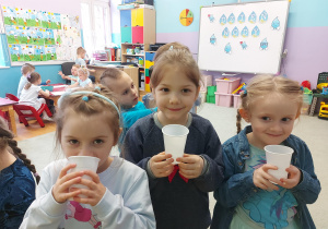 Dziewczynki piją wodę z plastikowych kubeczków.