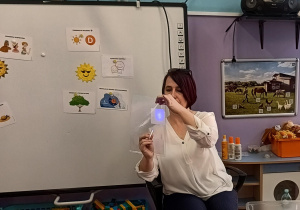 Pani Kamila prezentuje dzieciom doświadczenie ukazujące skuteczność działania kremu z filtrem UV