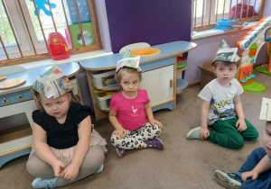 Dziewczynki z czapkami na głowach pozują do zdjęcia.
