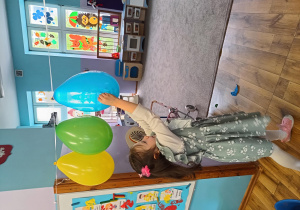 Dziewczynka przebija balon z ukrytym w środku zadaniem.