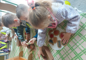 Dzieci przy stolikach wykonują ekologiczne zadania.