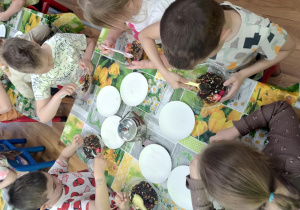 Dzieci siedzą przy stoliku i komponują swoje herbaty.