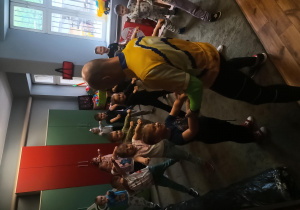 Dzieci stoją na dywanie i wykonują ciosy karate.