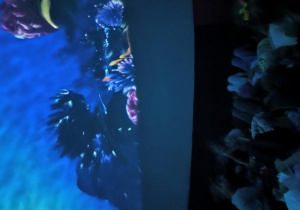 Dzieci leżą na podłodze w kopule projekcyjnej i oglądają projekcję "Ocean".