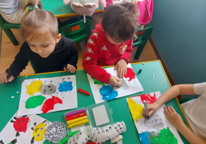Dwóch chłopców dorysowuje emocje na plamach z farby.