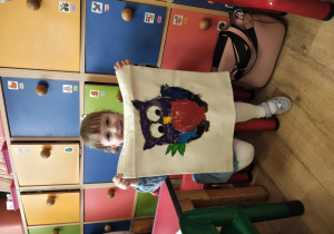 Dziewczynka trzymająca w rączkach pięknie pomalowaną wraz z mamą torbę.