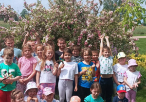 Zdjęcie grupowe dzieci na tle krzewu.