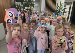 Grupa dzieci pokazuje własnoręcznie zrobione papierowe sowy.