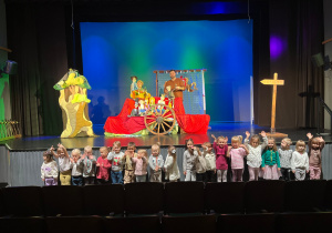 Dzieci pozują do zdjęcia z aktorami na tle scenografii.