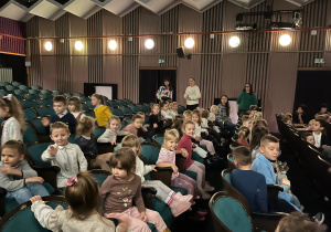 Dzieci zajmują miejsca siedzące w teatrze.