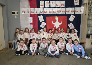 Dzieci z grupy trzeciej pozują do zdjęcia na tle dekoracji z okazji Dnia Niepodległości.