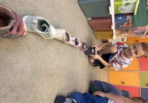 Chłopiec układa swój but w linii z innymi butami.