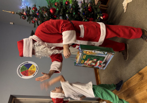 Mikołaj wręcza chłopcu prezent i przybija mu "piątkę".