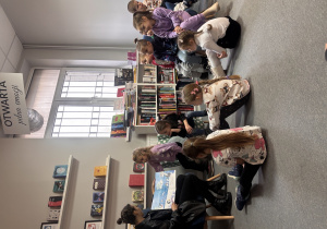 Dzieci słuchają opowiadania czytanego przez bibliotekarkę.