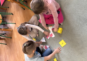 Troje dzieci układa puzzle na temat praw dziecka.