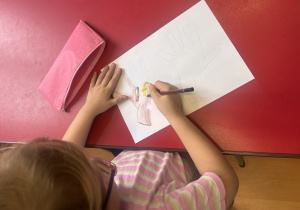 Dziewczynka rysuje wybrane prawo dziecka.