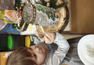 Dziewczynka malują farbą słoik.